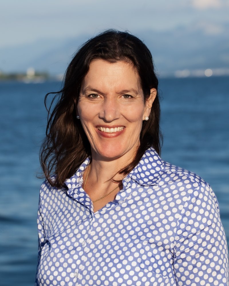 Frau lächelt vor blauem Wasser. Porträt einer sympathischen Person im Freien.