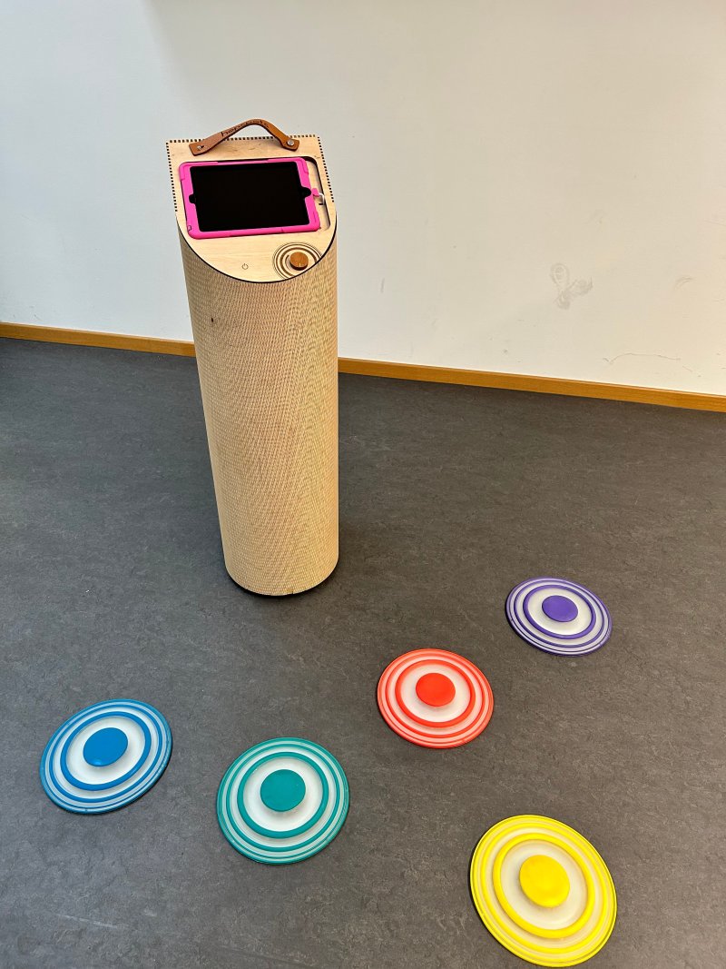 Interaktiver Spielturm mit Tablet und bunten Wurfscheiben für Kinder.
